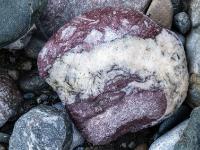Rotbrauner Stein mit breiter weißen Maserung in der Mitte und am Rand